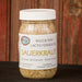 A jar of Sauerkraut, labeled 'Wild & Raw Lacto Fermented Sauerkraut', sitting on a dark wooden surface against a rustic reddish-brown wooden plank background.